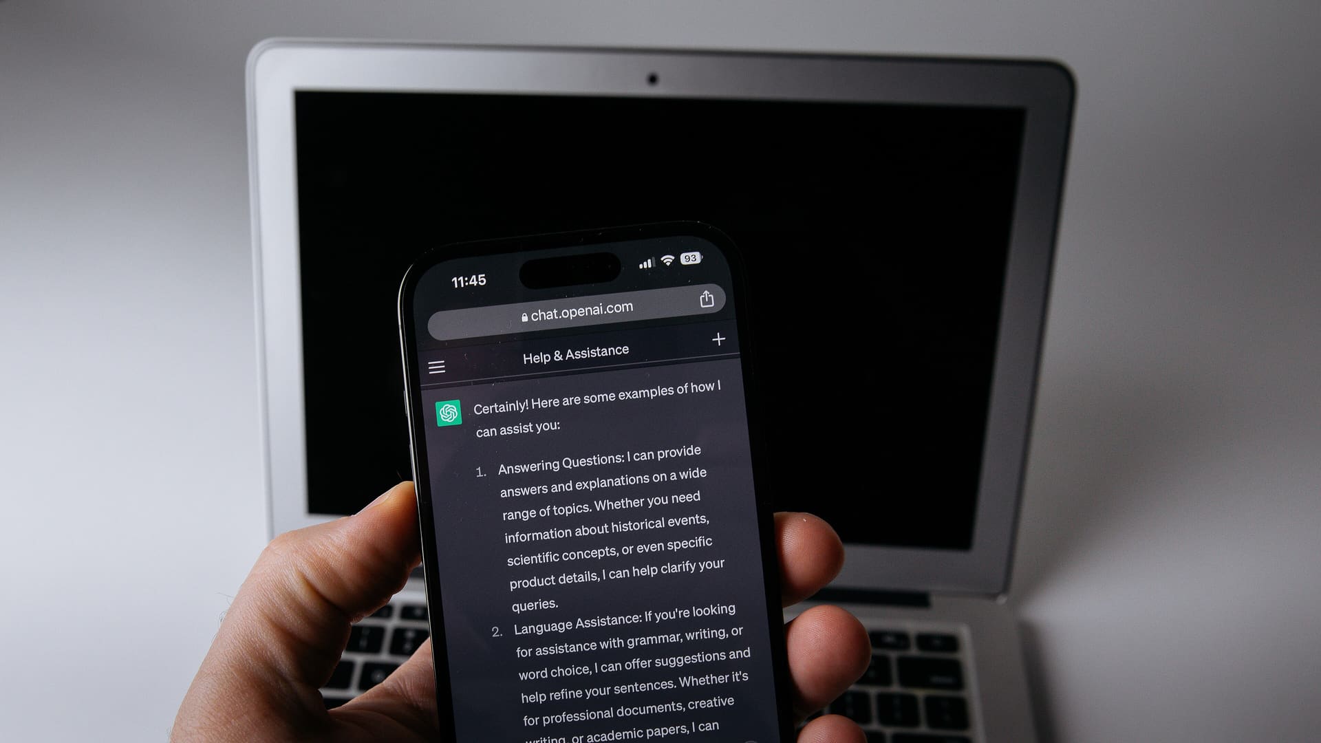 Smartphone displaying the ChatGPT app placed next to an open laptop