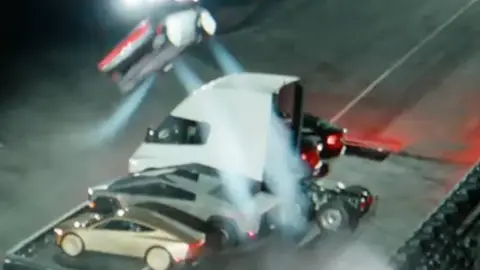 The Roadster flying through the air above a Tesla Semi, a Cybertruck and two cars