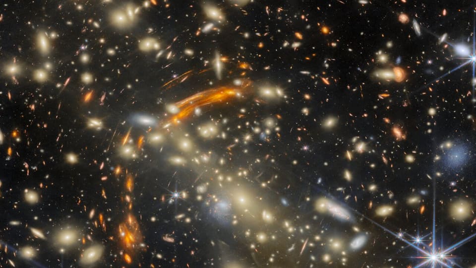 Webb image of galaxy cluster MACS J0454.1-0300, whose gravity distorts and repeats images of distant galaxies.