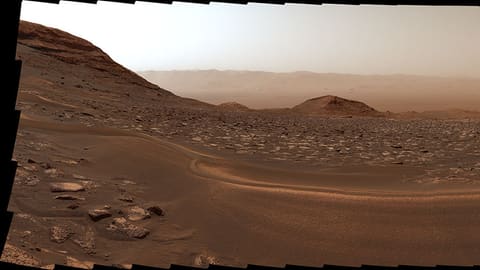 Curiosity panorama looking back over Gale Crater, with a sand ridge and a wheel-dug trench in the foreground
