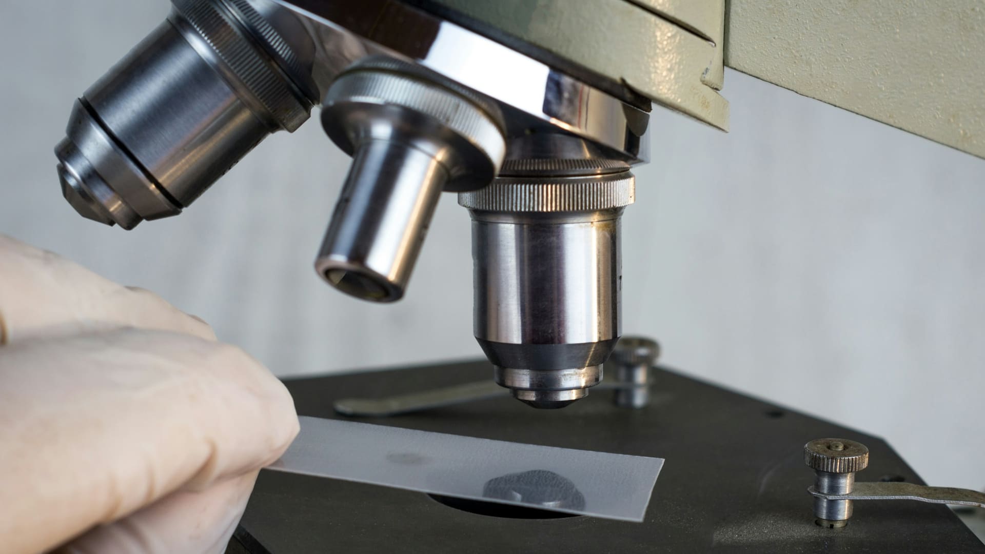 Researcher using a microscope to examine metal in laboratory