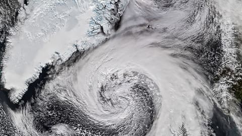 Extratropical cyclone with comma-shaped cloud formation swirling near Iceland