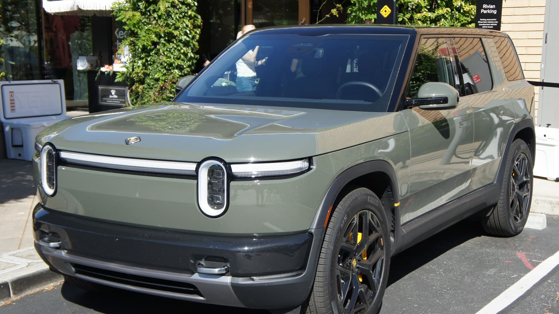 Green Rivian R2 SUV parked outside the Rivian Space store at Stanford Shopping Center in Palo Alto, California