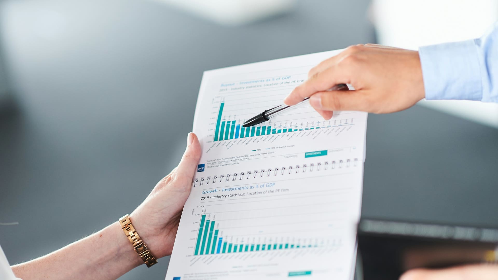 Two professionals analyzing financial documents with green bar charts together