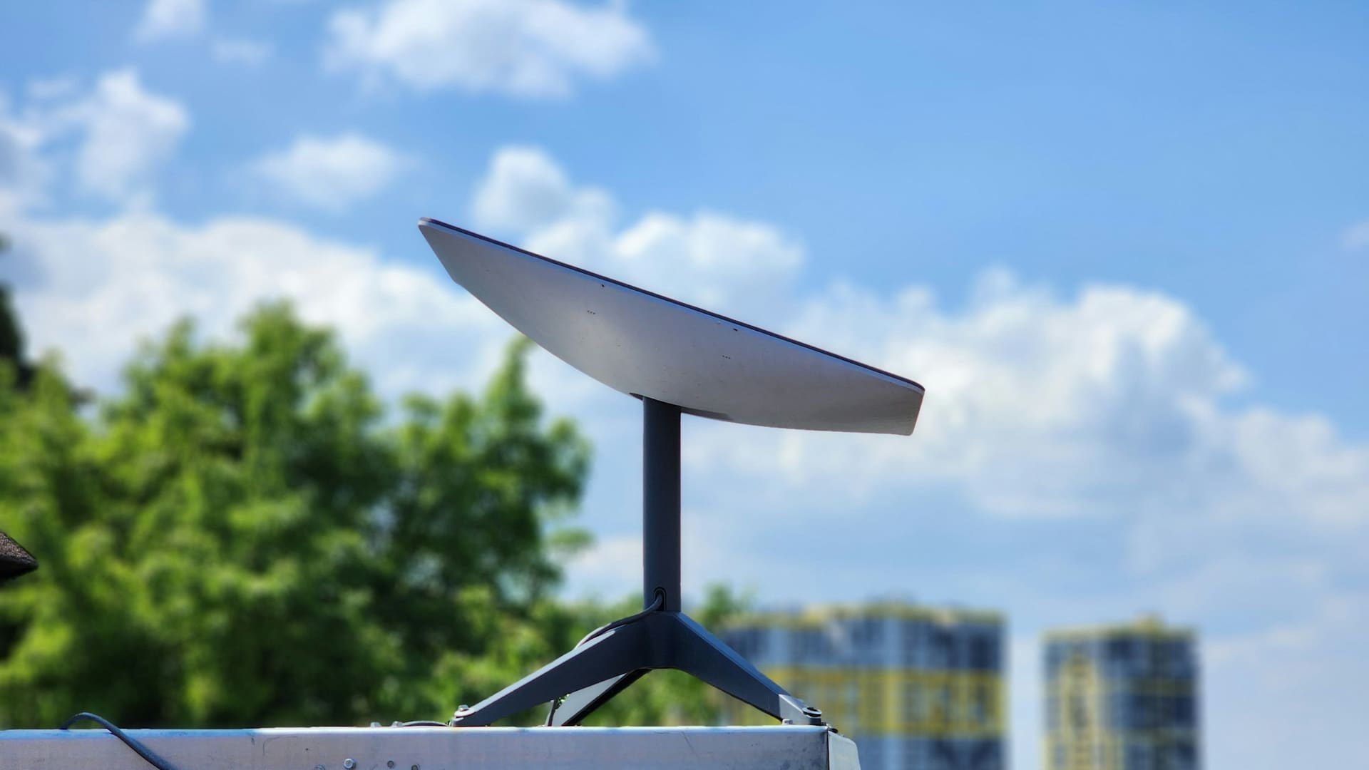 A white Starlink communications terminal mounted on a metal pole.