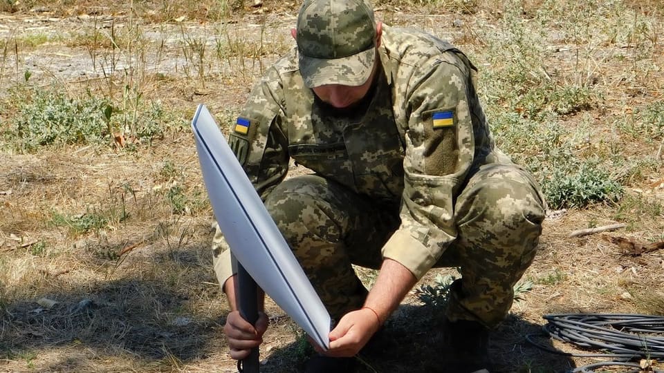 Ukrainian soldier installing a Starlink terminal in the field