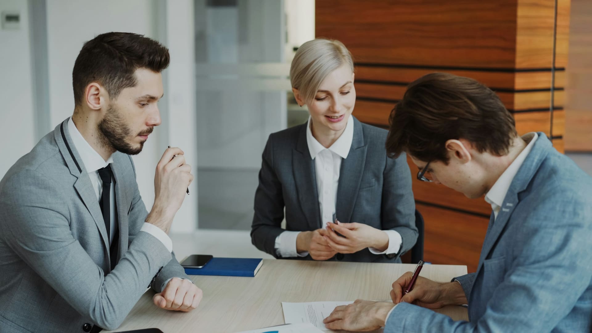 Business colleagues and corporate lawyer reviewing contract at table
