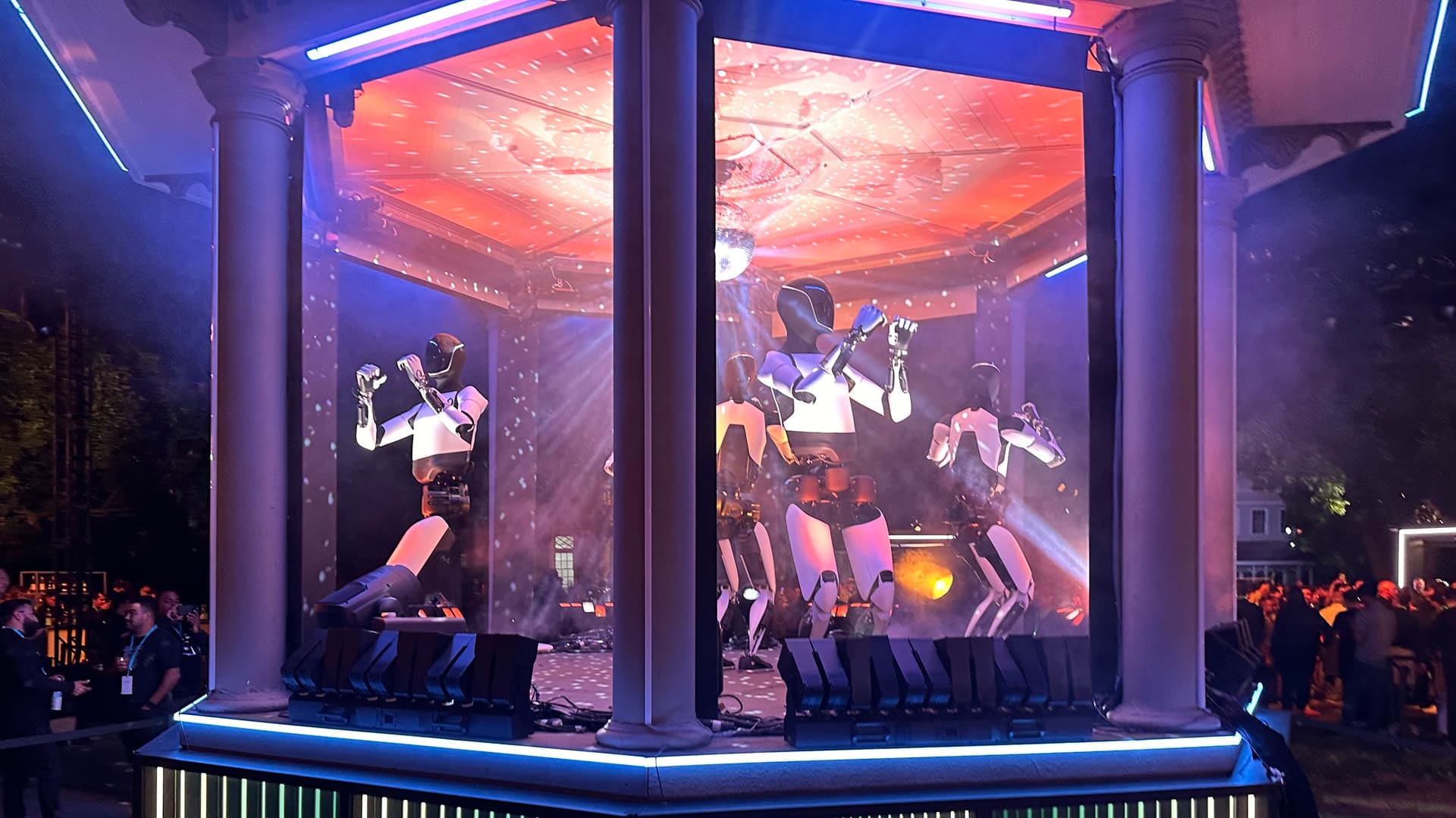 Tesla Optimus humanoid robots dancing among the crowd at Tesla's Robotaxi event at Warner Bros. studios