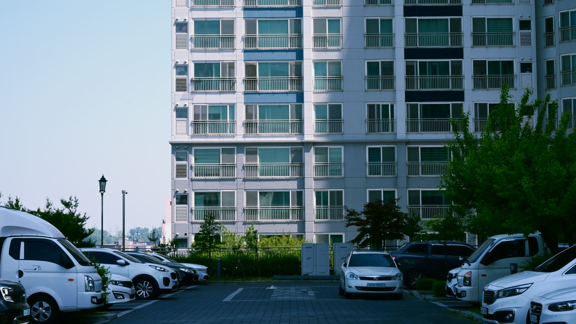 Apartment building overlooking parking lot with multiple parked vehicles