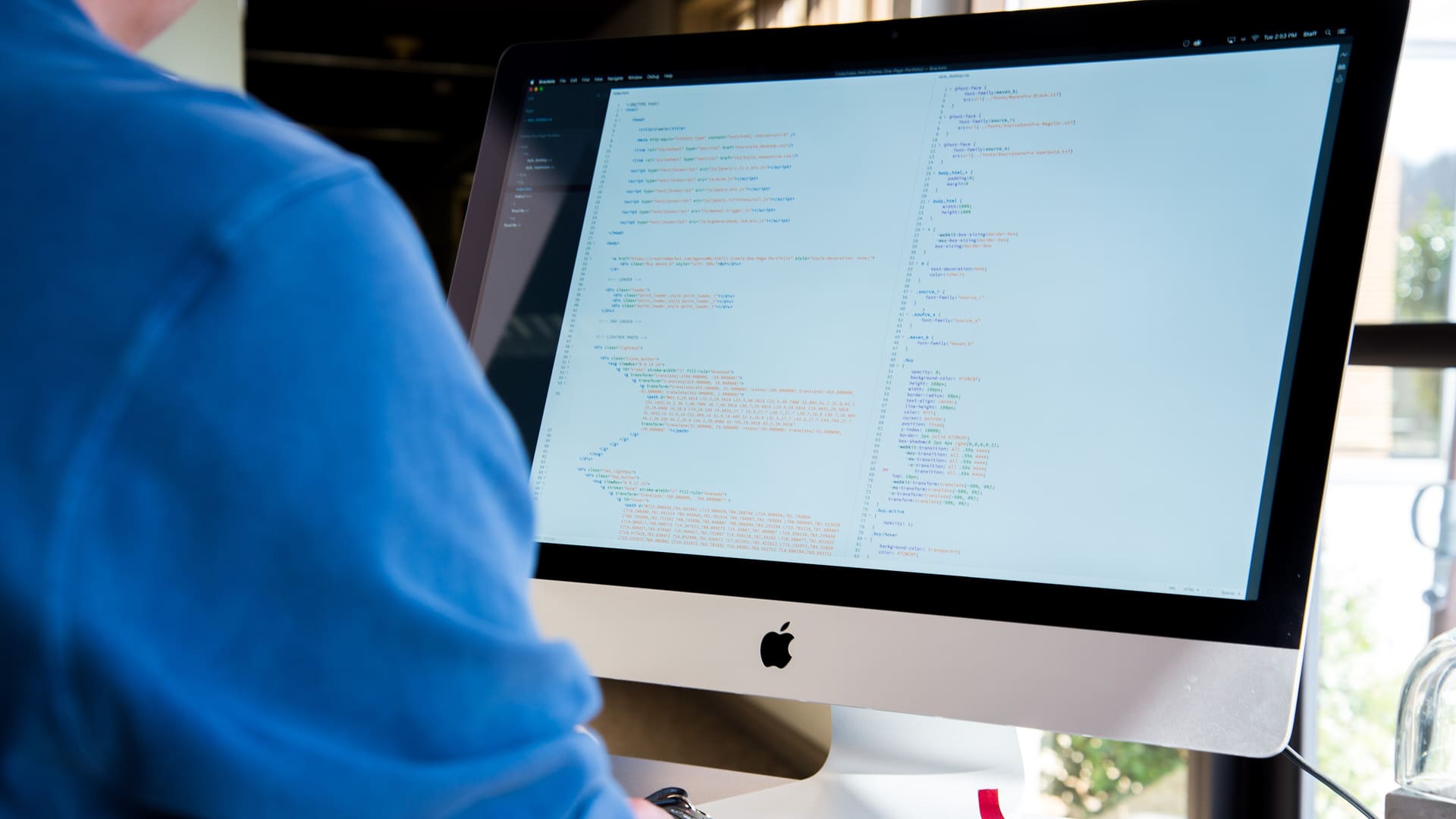 A software developer working at an iMac computer.