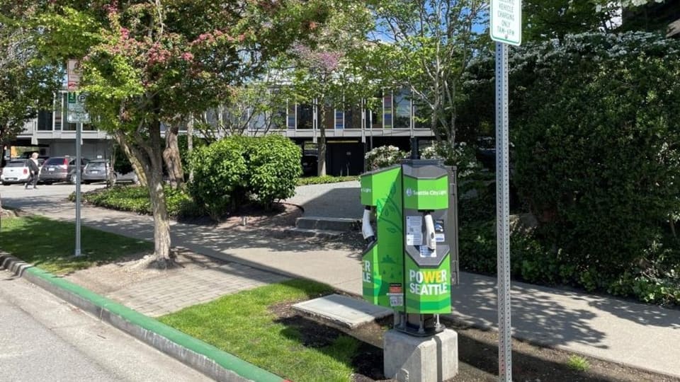 Level 2 electric vehicle charger mounted at Seattle curb with vehicle charging