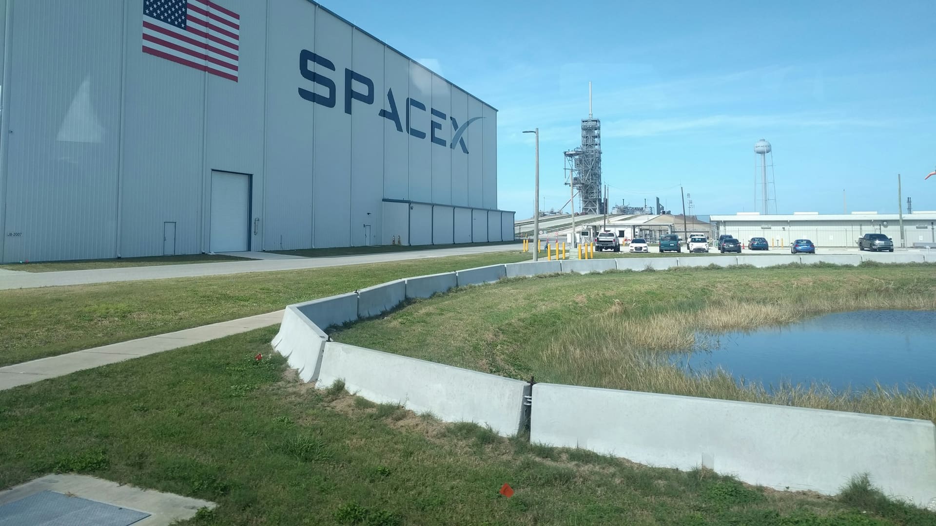 SpaceX launch pad buildings beside a grassy field at Kennedy Space Center in Florida.