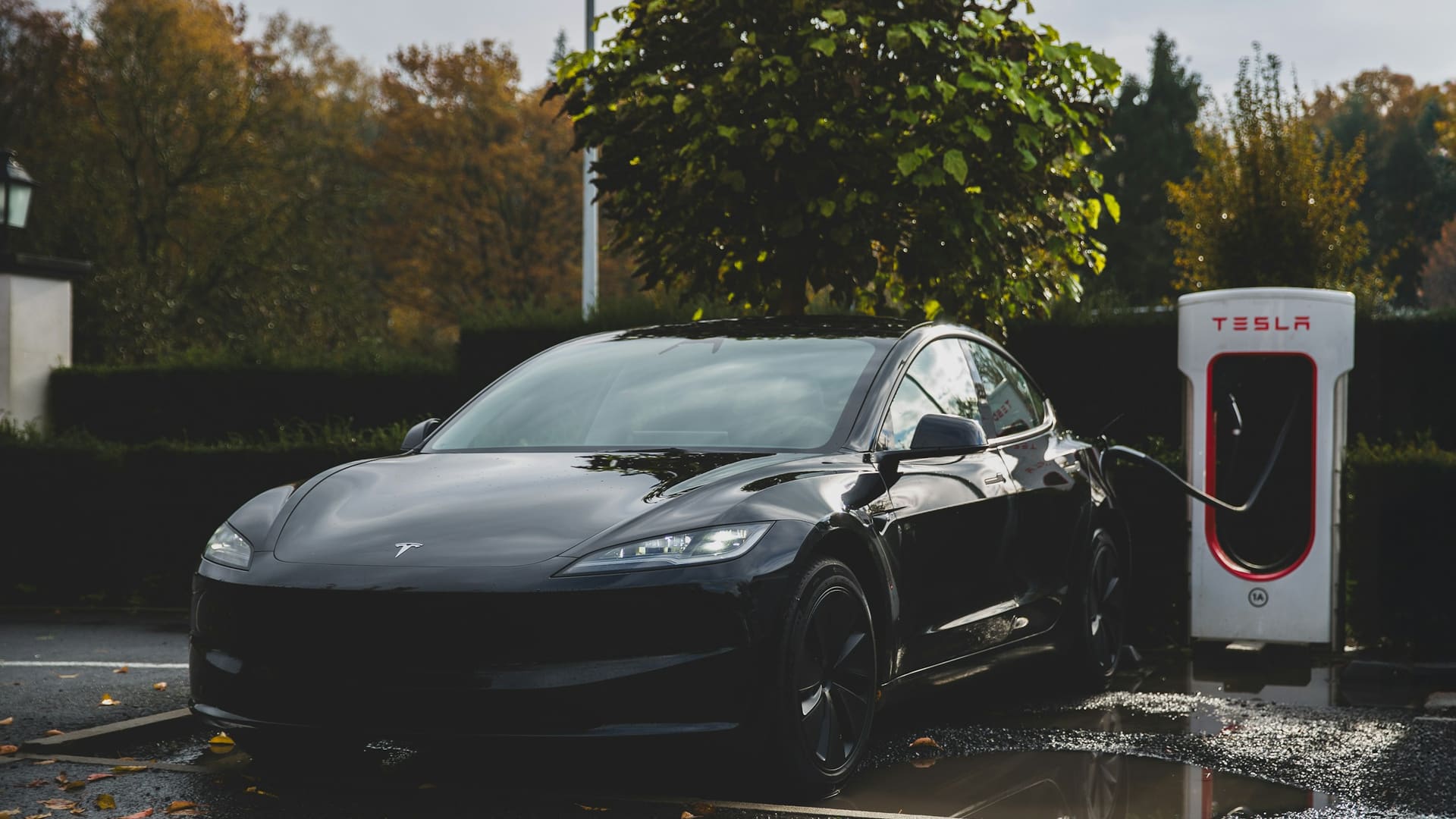 A Tesla Model 3 Highland charging at a Tesla Supercharger station.