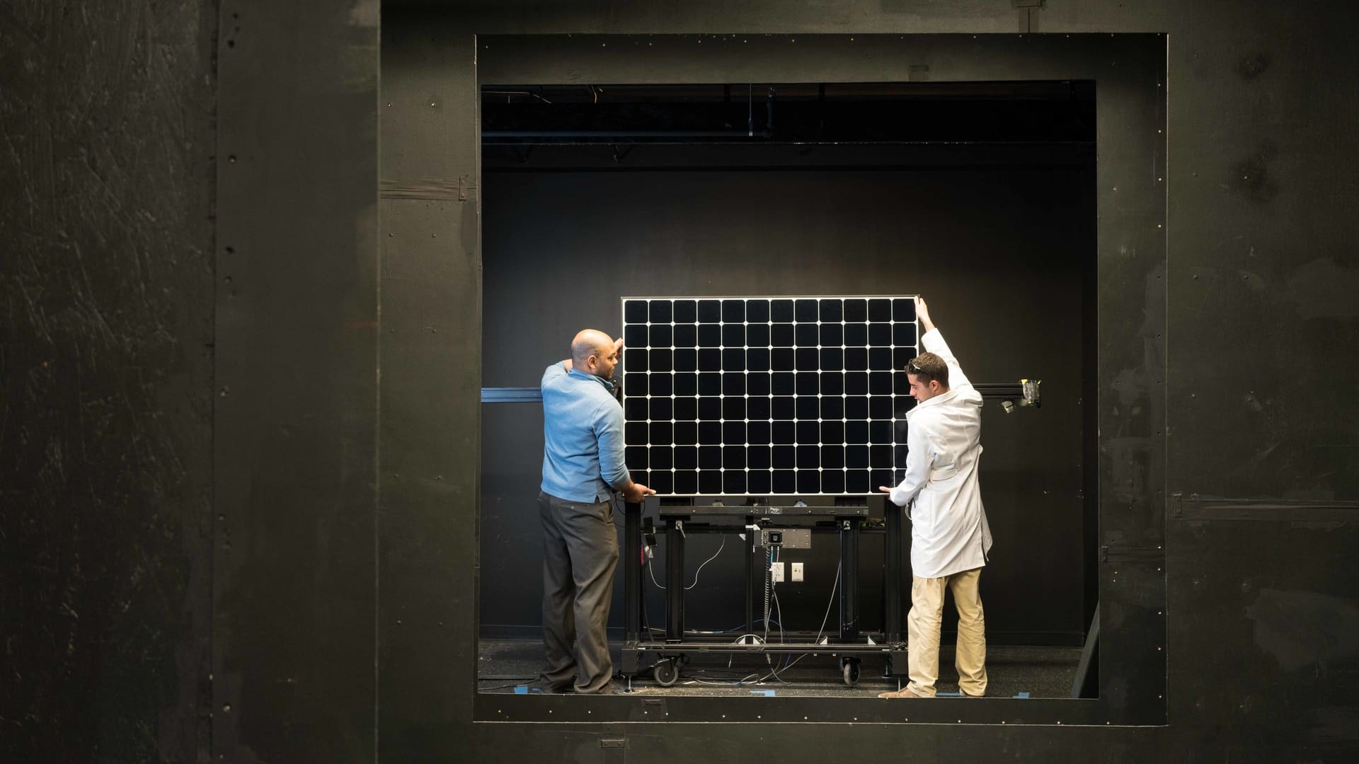 Researchers mounting a photovoltaic module for performance testing in a laboratory